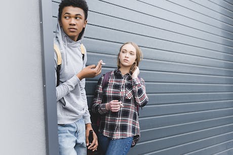 Students smoking behind a building.